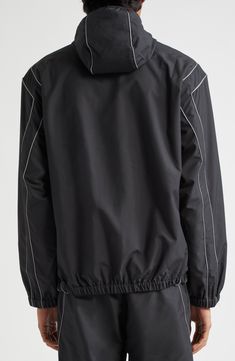 The designer leans into the easy wearability of athleisure with this lightweight windbreaker refreshed with a protective hood and reflective piping tracing the shoulders and sides. Front zip closure Drawcord-toggle hood Elastic cuffs Side-seam pockets; interior pocket Reflective details enhance visibility in low light or at night Mesh lining 100% polyester Dry clean Imported Designer Clothing Black Nylon Hooded Jacket Athleisure, Black Nylon Athleisure Hooded Jacket, Functional Track Jacket With Double-lined Hood For Streetwear, Black Techwear Track Jacket With Drawstring Hood, Black Nylon Windbreaker With Functional Drawstring, Black Windbreaker With Functional Drawstring, Techwear Hooded Track Jacket With Reflective Details, Black Sportswear Windbreaker With Drawstring Hood, Technical Outerwear With Double-lined Hood For Streetwear