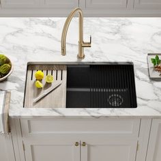 a kitchen sink with marble counter tops and white cupboards in front of it, next to a bowl of green vegetables