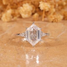 a diamond ring sitting on top of a table next to some dried flowers in the background