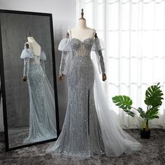 a dress on display in front of a mirror with mannequins behind it