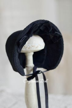 a white mannequin head with a black hat on it's top and ribbon around the brim