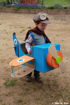 a little boy dressed up as a toy airplane with a cardboard box attached to it