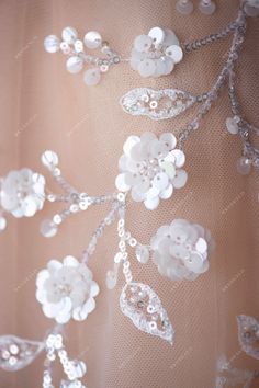 the back of a wedding dress with flowers and pearls on it's laces