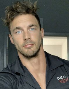 a man with blue eyes is posing for the camera