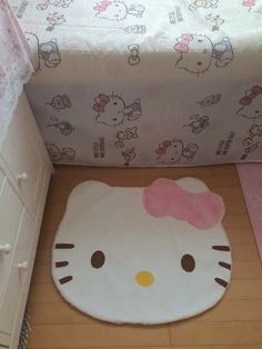 a hello kitty rug in the corner of a room next to a bed and dresser