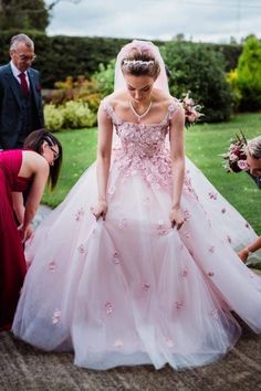 a woman in a pink wedding dress standing next to other people