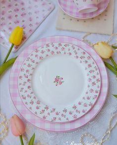 a pink and white plate sitting on top of a table next to tulips