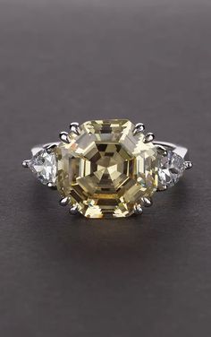 a fancy yellow diamond ring with three diamonds on the sides and an oval shaped center stone