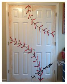 two white doors with red ribbons on them in the shape of baseballs and bats