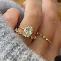 a woman's hand with a diamond ring on top of her finger and the other hand holding it