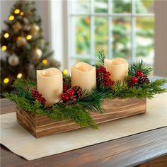 candles are sitting on a wooden tray with greenery and pine cones in front of a christmas tree