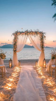 Elegant wedding ceremony setup on the beach. Flowing white drapes, floral arch with soft pastel blooms, and sandy accents. Ambient fairy lights create a romantic glow. Captured in golden hour light. Beach Wedding Altar, Beach Marriage, Luxury Beach Wedding, Cute Proposal Ideas, Dream Beach Wedding, Dream Wedding Decorations, Wedding Venues Beach, Wedding Proposals, 25th Wedding Anniversary