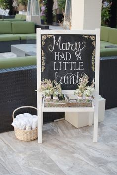 a chalkboard sign sitting on top of a table next to a basket filled with flowers