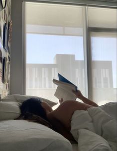 a woman laying in bed reading a book