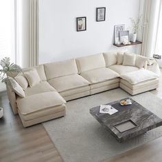 a living room with a large sectional couch and coffee table in the middle, along with pictures on the wall