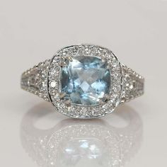 an aqua blue and white topazte ring with diamonds on the sides, set in 18k white gold