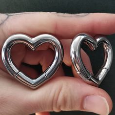 two heart shaped metal objects in the palm of someone's hand