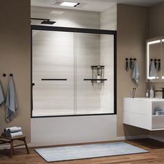 a bathroom with a walk in shower next to a white sink and wooden flooring