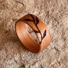 a wooden ring with an etched branch on it's side sitting on the ground