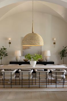 a dining room table surrounded by chairs and vases with plants in them on the tables