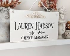 there is a sign that says lauren hudson office manager on the shelf next to flowers