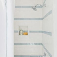 a bathroom with blue and white tiles on the walls, shower head, and bathtub