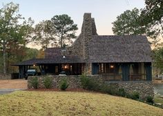 a stone house with a car parked in front of it and trees around the building