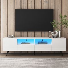 an entertainment center with a flat screen tv mounted on it's sideboard in front of a wooden wall