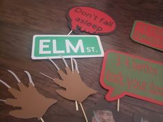 several handprinted signs and stickers sitting on a table with wooden sticks in the shape of leaves