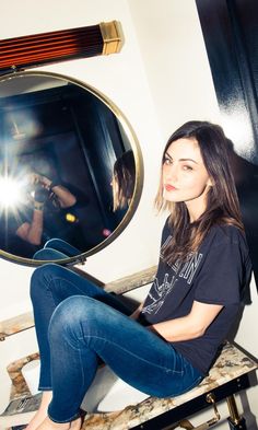 a woman sitting on a stool in front of a mirror taking a selfie with her camera