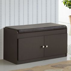 a brown storage box sitting on top of a white floor next to a plant and wallpaper