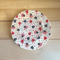 an american flag plate with stars and hearts on it sitting on a wooden table top