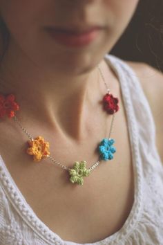 a woman wearing a necklace with crochet flowers on it