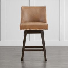 a brown bar stool sitting on top of a hard wood floor next to a white wall