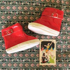 two pairs of red shoes sitting on top of a rug next to an old book