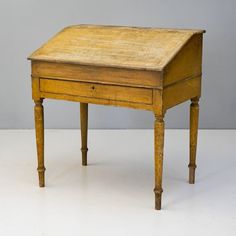 an old wooden desk sitting on top of a white floor