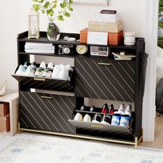 a black and gold cabinet with shoes on it in a living room next to a plant