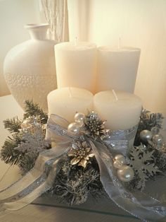 some candles are sitting on a table with silver ribbon and snowflakes around them