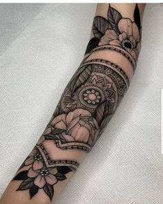 a woman's arm with tattoos on it and flowers in the middle of her arm