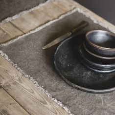 a wooden table topped with two black bowls and a knife next to a pair of scissors