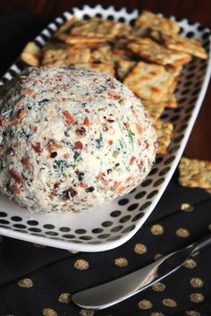 a cheese ball sitting on top of a white plate next to crackers