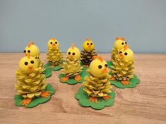 small yellow chicks sitting on top of green leaves and pinecones with one chick in the center