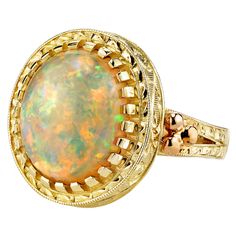 The 4.30 carat opal in this handmade 18k yellow gold ring is bursting with color! This gemstone displays flashes of bright green, orange, yellow, and the most highly-prized and rare color: red! It is difficult for photos to do this opal justice. This ring was custom-designed by our Master Jewelers in Los Angeles in order to showcase the high dome, depth of color and life in this gem. The sides of the ring have been hand engraved and show a level of artisanship and skill seldom seen today. A ring like this requires untold hours to bring to life, but will be enjoyed and treasured for years! Size 7 Complimentary sizing as needed Gem Ring, 18k Yellow Gold Ring, Domed Ring, Yellow Gold Ring, Gems Jewelry, Hand Engraving, Bright Green, Green Orange, Yellow Gold Rings