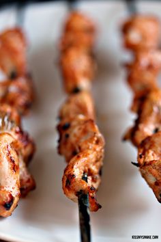 several skewers of chicken on a white plate