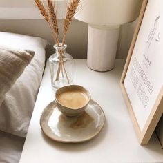 a cup of coffee sitting on top of a white plate next to a framed photograph