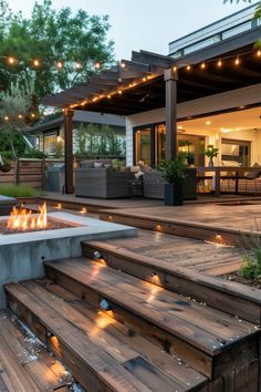 a fire pit sitting in the middle of a wooden deck next to a patio with lights on it