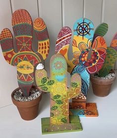 several colorful painted wooden cactus sculptures next to potted plants on a white background with an instagram caption below that reads,'me gustia contemar com