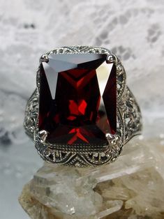 Garnet Cubic Zirconia (CZ) Ring Autumn Design #D200 Inspired by Victorian era designs, this lovely filigree reproduction has been recreated in sterling silver. This flawless 5 carat red garnet cubic zirconia gemstone is 12mm x10mm in size. The ring sits 17mm (11/16") North to South on the finger. The inside of the band is etched 925 for sterling silver. Notice the intricate and detailed design of the antique silver filigree setting all the way down the band. This is an exquisite rendition of an Garnet Ruby Ring With Intricate Design As Gift, Classic Red Ruby Ring With Square Cut, Classic Square Cut Ruby Ring Gift, Classic Square-cut Ruby Ring, Classic Red Square Cut Jewelry, Ruby Ring With Intricate Design For Wedding, Classic Red Square-cut Jewelry, Ornate Garnet Ruby Ring As Gift, Classic Red Ruby Ring With Intricate Design