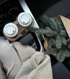 the interior of a car with coffee cups and napkins on it, next to a christmas tree