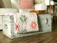 an old trunk is sitting on the floor in front of a white couch and chair